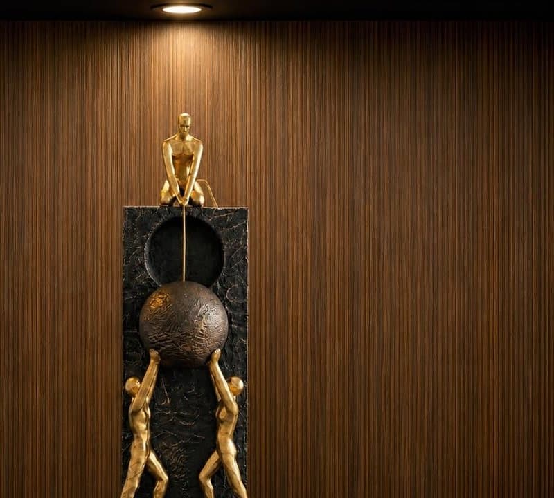 Gold figures lifting a dark sphere