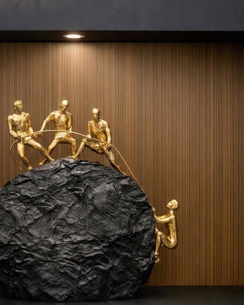 Gold climbers sculpture on dark stone